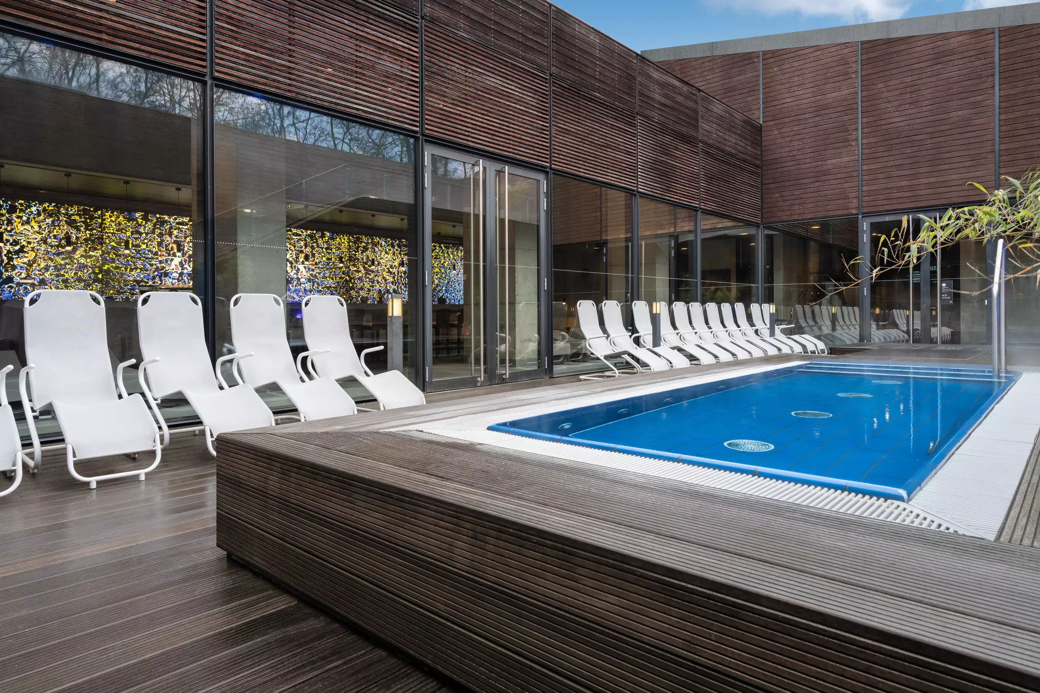 A pool terrace with a small rectangular pool with several loungers around the outside.
