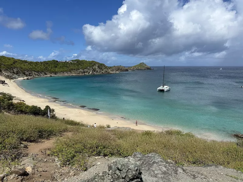 A sparse beach with one boat floating in its waters