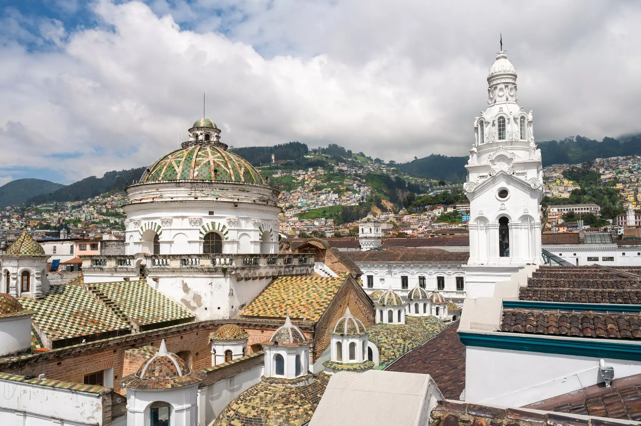 Several white domed rooftops of a cathedral in Quito, Ecuador. A view of a piece of the city skyline. 
