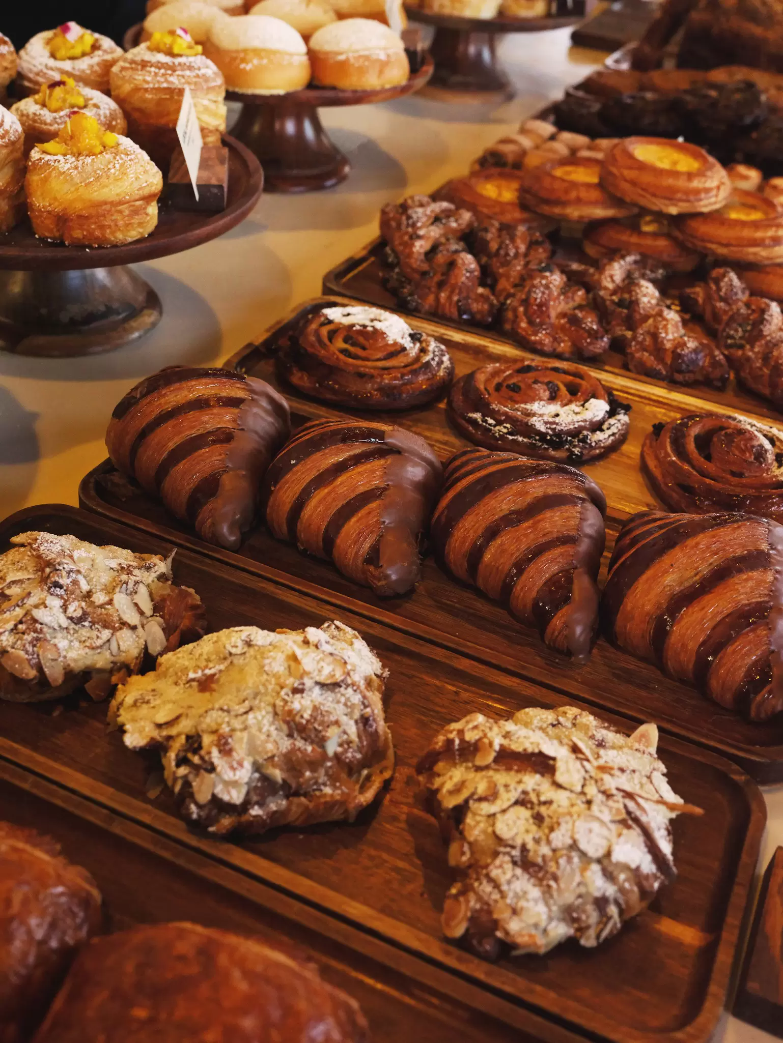 An assortment of pastries on display on wooden boards at a bakery