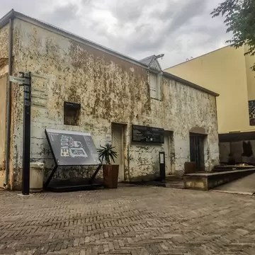 Weathered old building with peeling plaster, wayfinding signs and a site map on a brick-paved courtyard