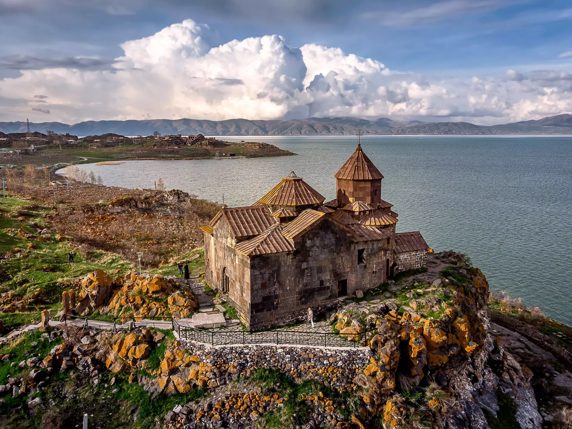 Dramatic clouds rise behind Hayravank Monastery on the shores of Lake Sevan, Armenia.