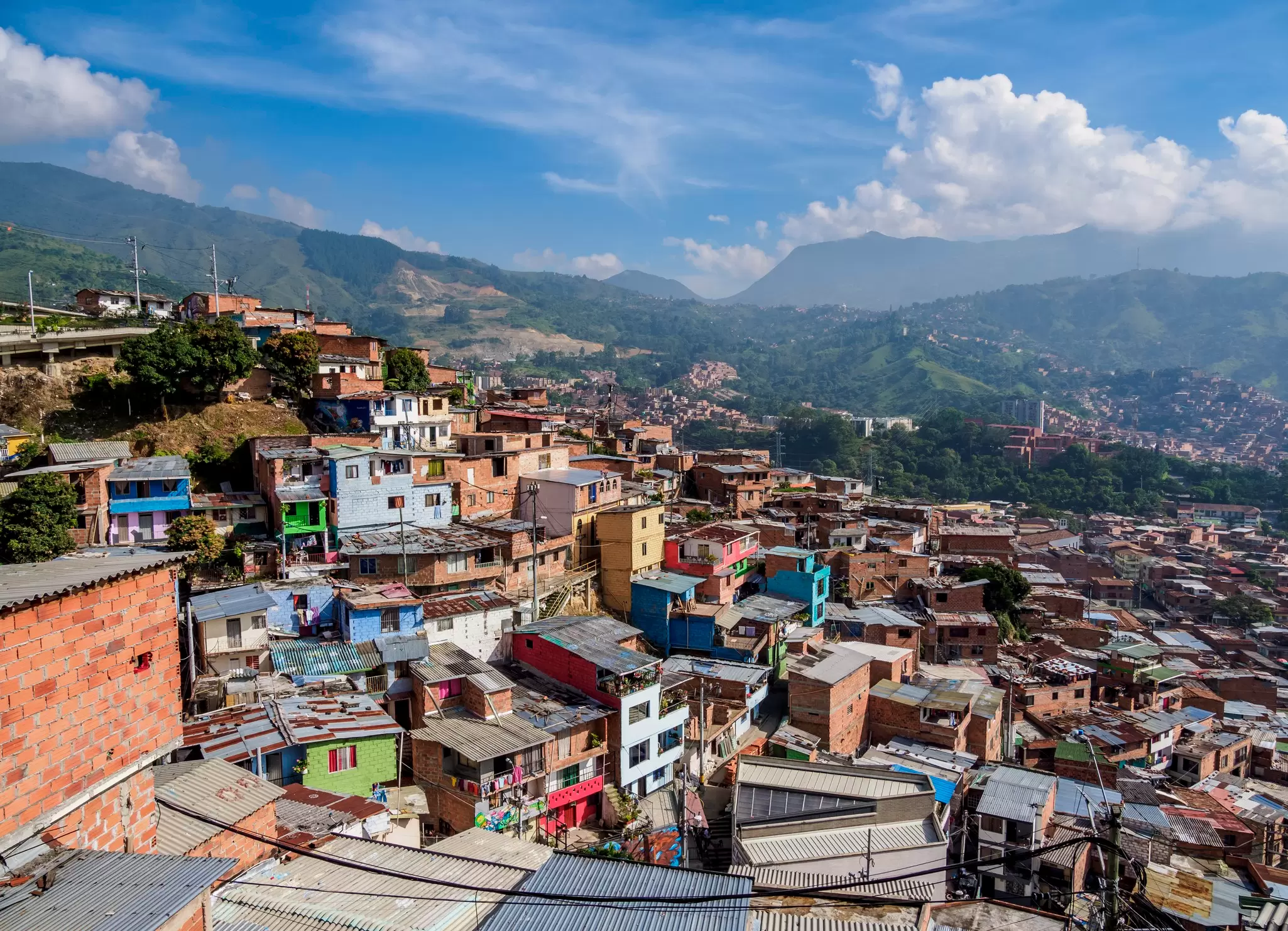 A view of a city neighborhood with small colorful houses hugging a hill in a valley.