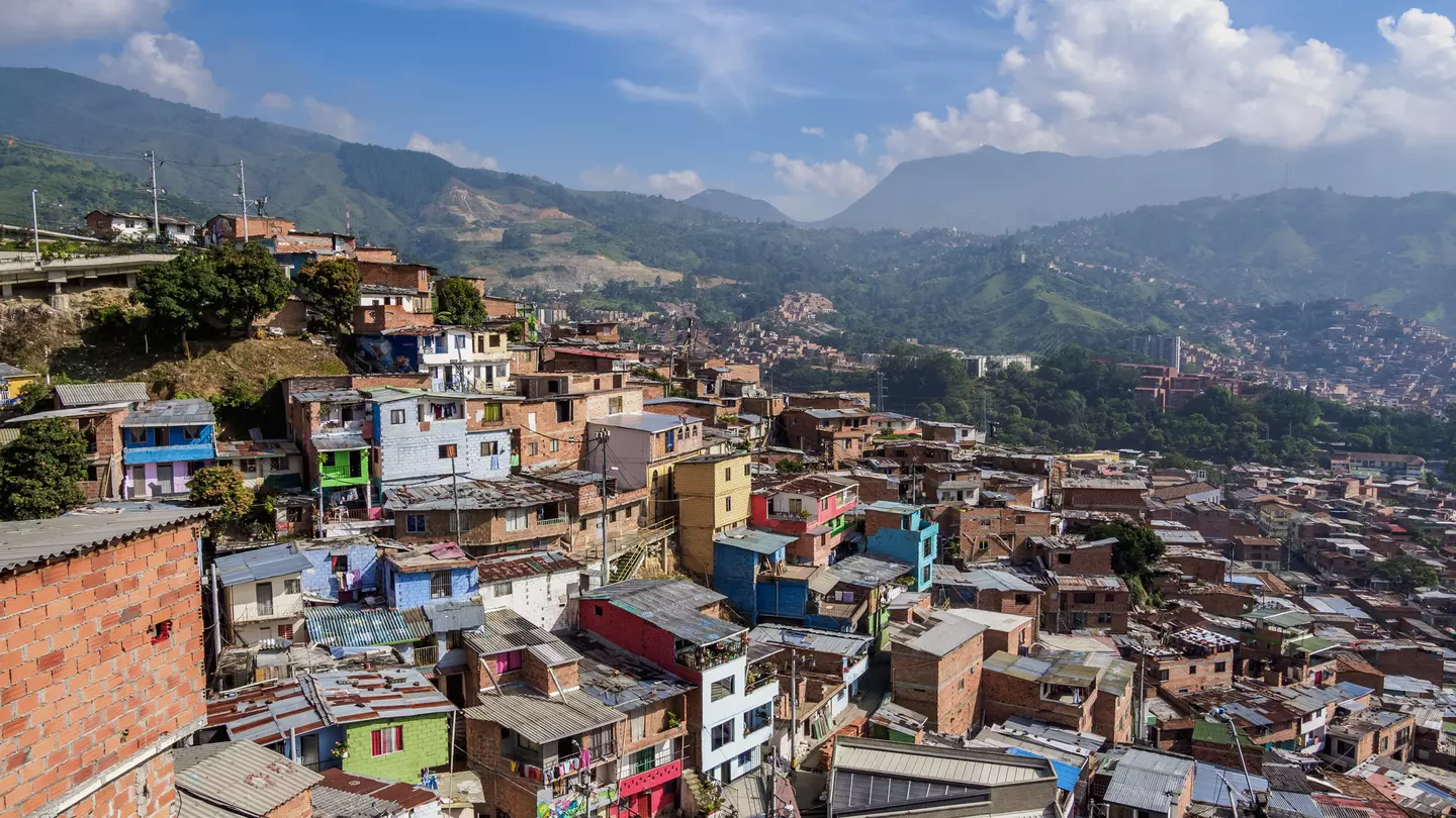 A view of a city neighborhood with small colorful houses hugging a hill in a valley.
