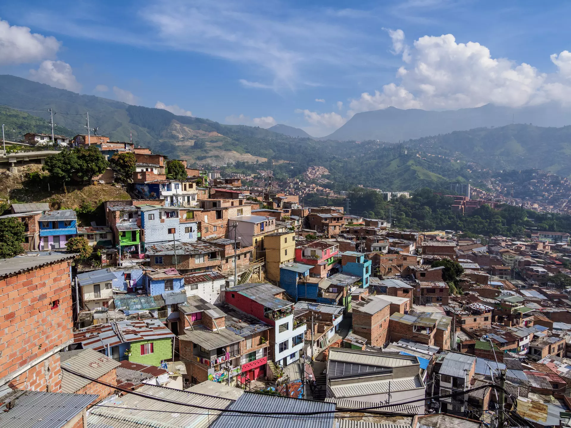 A view of a city neighborhood with small colorful houses hugging a hill in a valley.