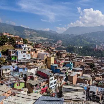 A view of a city neighborhood with small colorful houses hugging a hill in a valley.