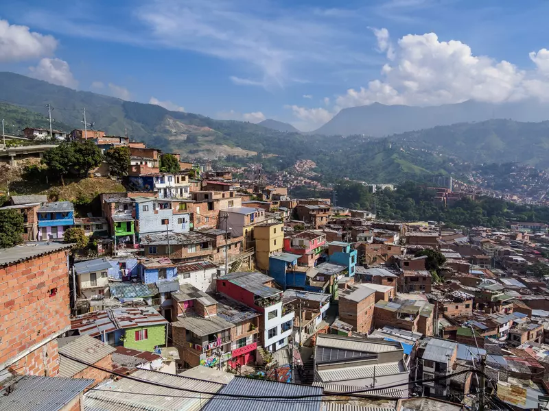 A view of a city neighborhood with small colorful houses hugging a hill in a valley.