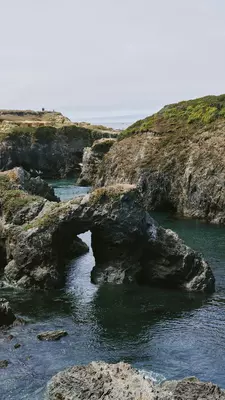 A rocky rugged coast line with a hole through a rock formation