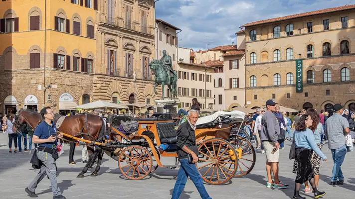 Palazzo Vecchio view with big crowd and horse carriage.