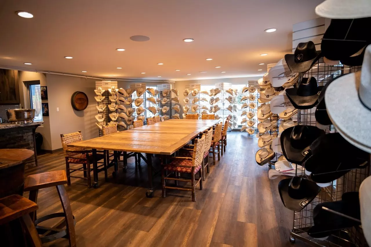 A store with a large central table lined with hat stands loaded with different forms of cowboy hat.