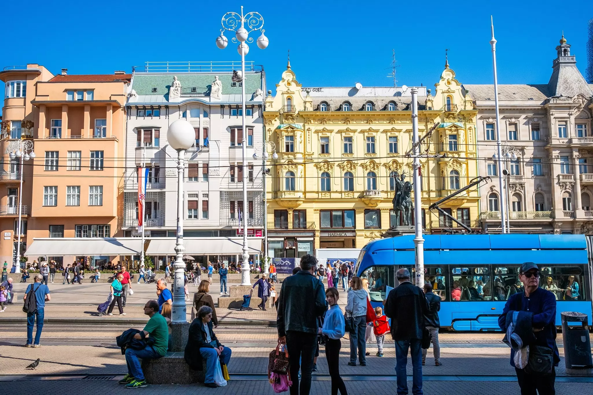 Historic buildings in pastel towns contrast against the blue tram in Zagreb