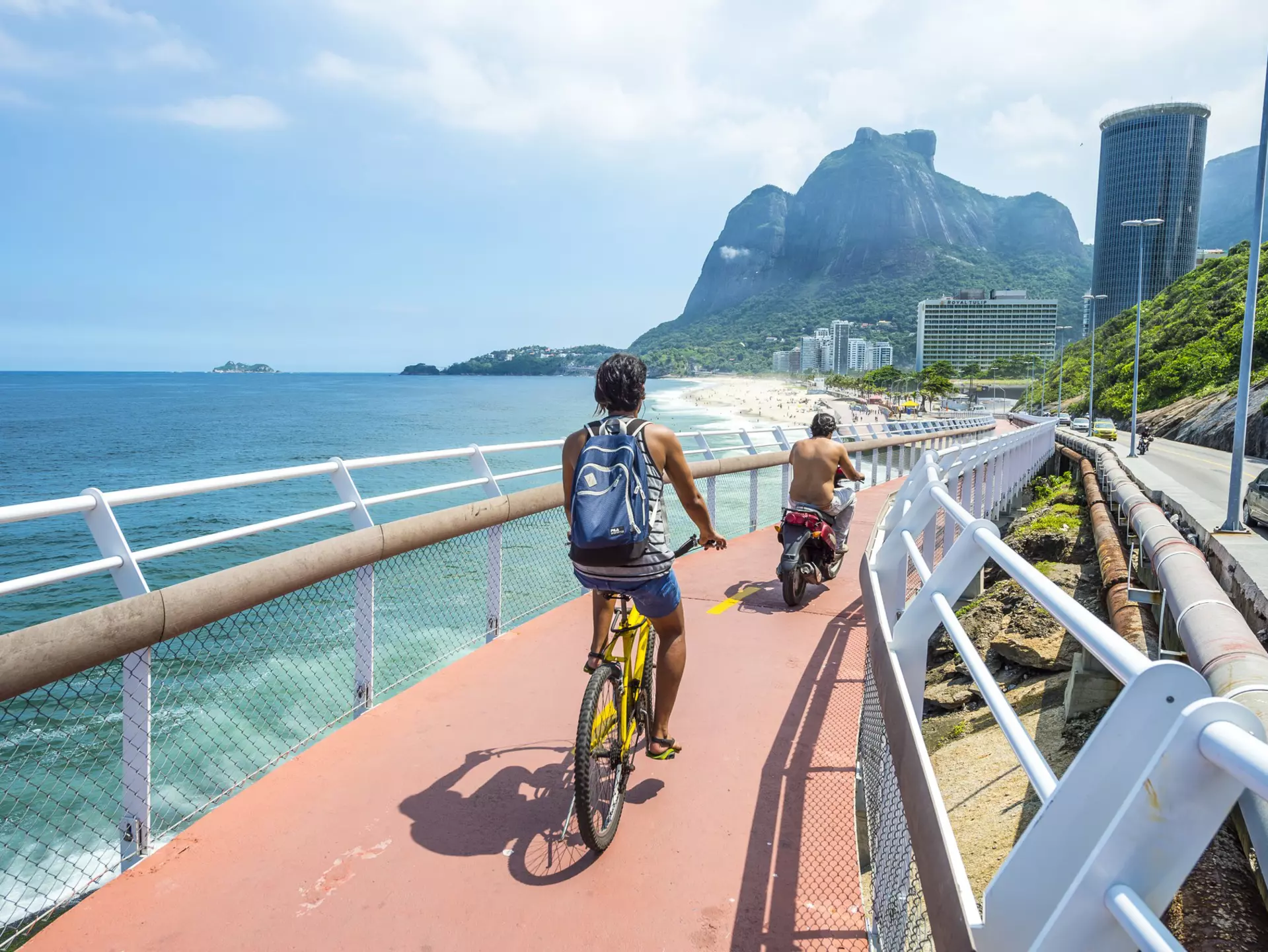 RIO DE JANEIRO - MARCH 19, 2016: Cyclist and scooter share the newly completed Ciclovia Tim Maia bike path, a legacy project from the 2016 Olympic Games connecting Ipanema and Copacabana with Barra., License Type: media, Download Time: 2025-05-22T13:23:20.000Z, User: lonelyplanetmedia, Editorial: true, purchase_order: 65050 - Digital Destinations and Articles, job: Global Publishing WIP, client: Global Publishing WIP, other: Pia Peterson Haggarty // SS Comp Ingestion