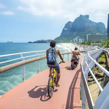 RIO DE JANEIRO - MARCH 19, 2016: Cyclist and scooter share the newly completed Ciclovia Tim Maia bike path, a legacy project from the 2016 Olympic Games connecting Ipanema and Copacabana with Barra., License Type: media, Download Time: 2025-05-22T13:23:20.000Z, User: lonelyplanetmedia, Editorial: true, purchase_order: 65050 - Digital Destinations and Articles, job: Global Publishing WIP, client: Global Publishing WIP, other: Pia Peterson Haggarty // SS Comp Ingestion