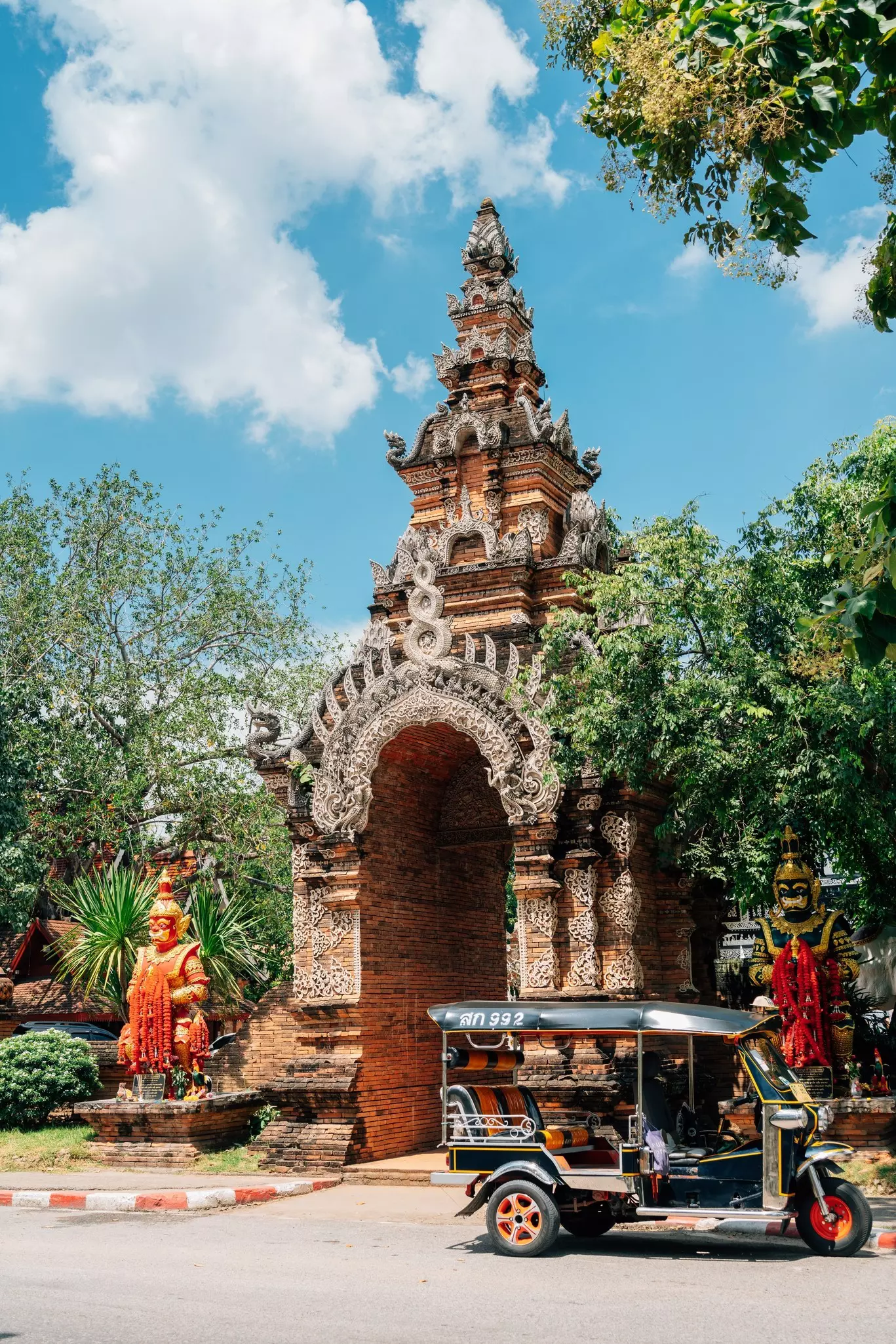 A black three-wheeled vehicle without doors in front of an ornate temple entrance