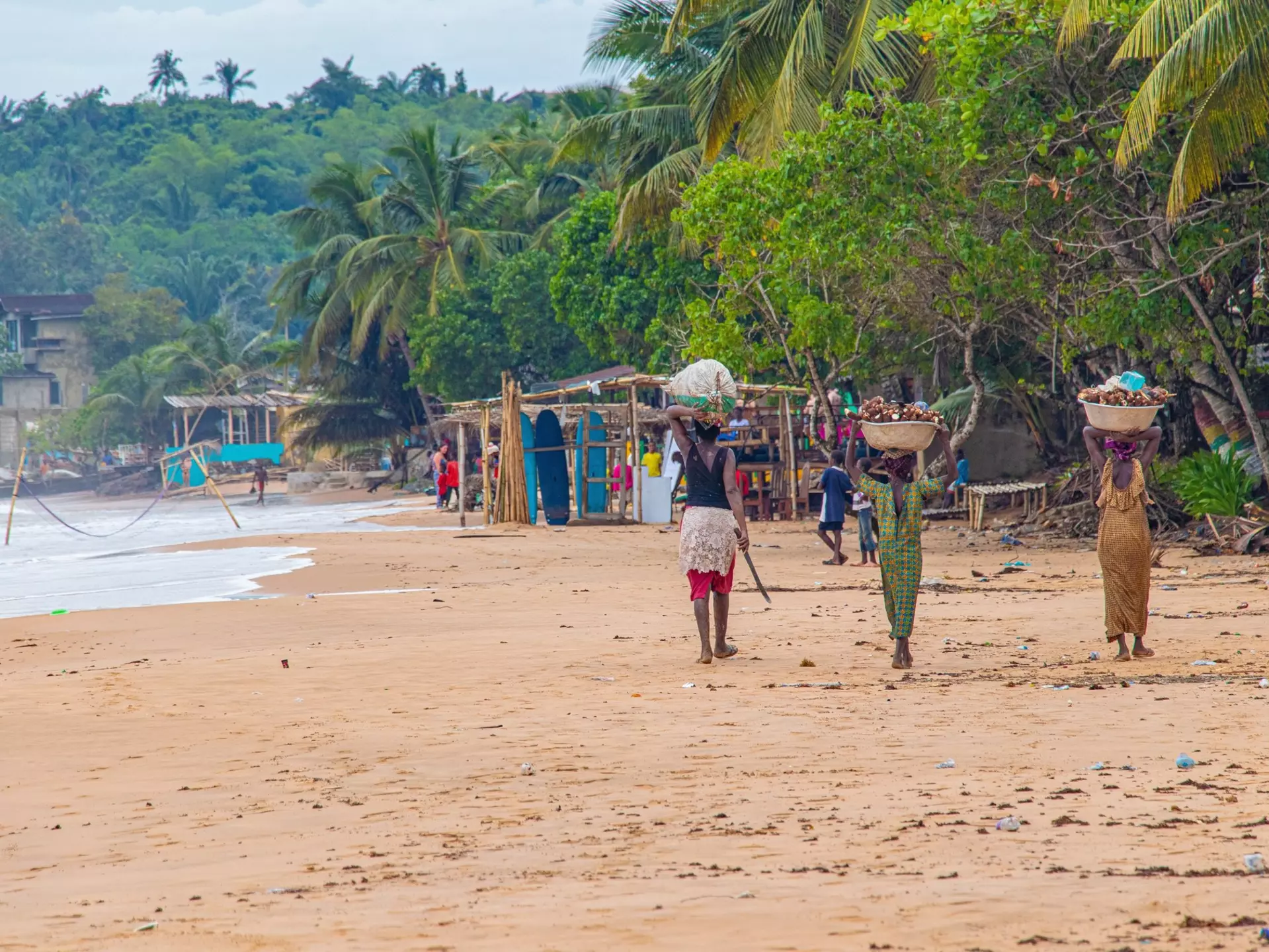 Busua, Ghana - May 10th, 2024: The people of Ghana. Local African women carrying basket while walking on the beach., License Type: media, Download Time: 2024-07-04T06:33:53.000Z, User: mvm_lonelyplanet, Editorial: true, purchase_order: 56530, job: Global Publishing-WIP, client: The World 3, other: Virginia Moreno