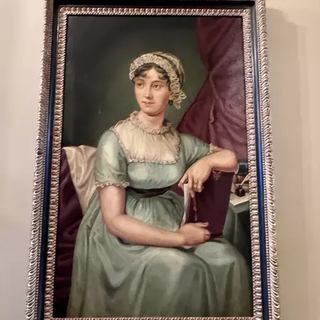 A painting of a seated woman wearing a Regency-style pale blue dress and bonnet.