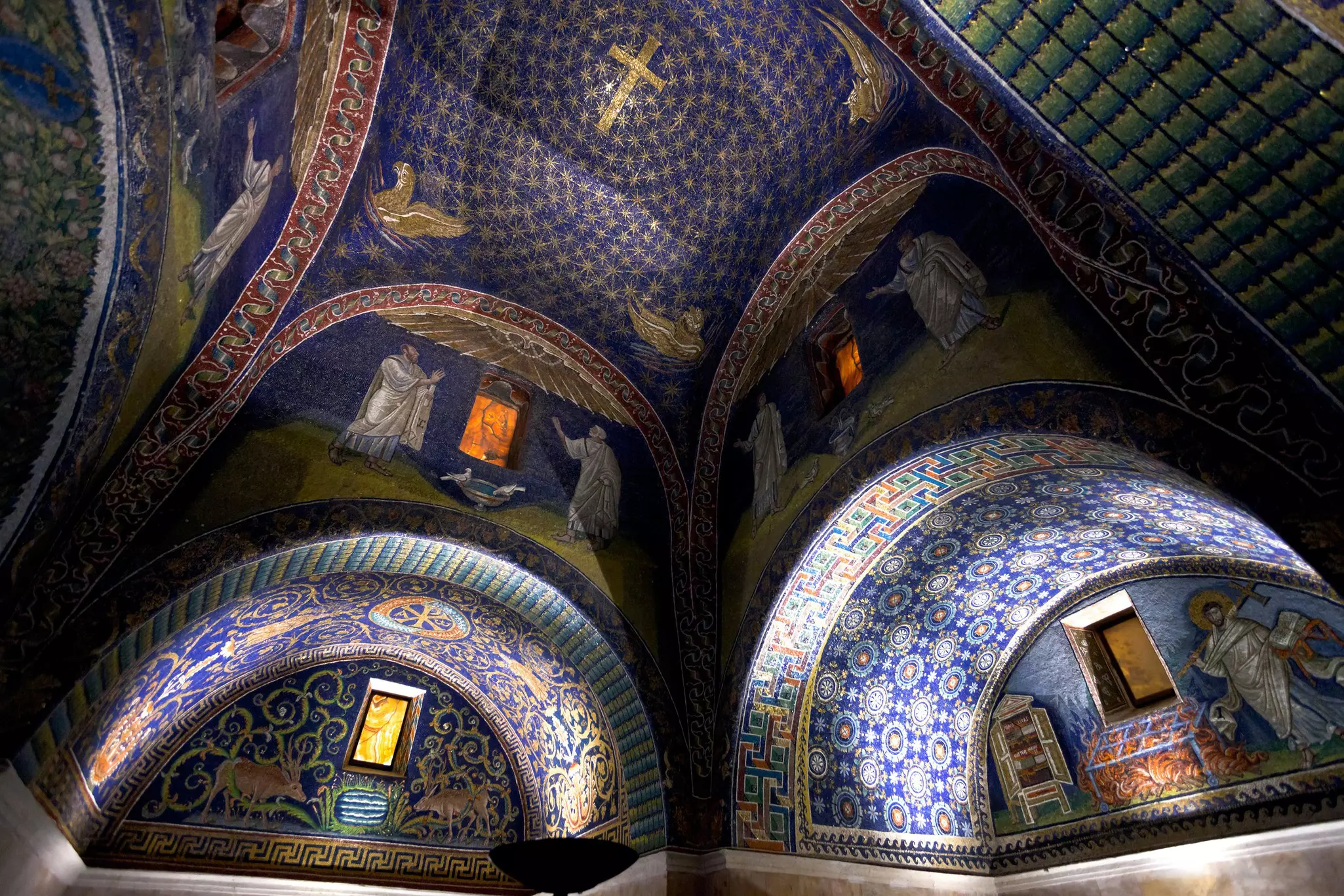 A series of blue-tiled mosaics cover the arched ceiling of a mausoleum 