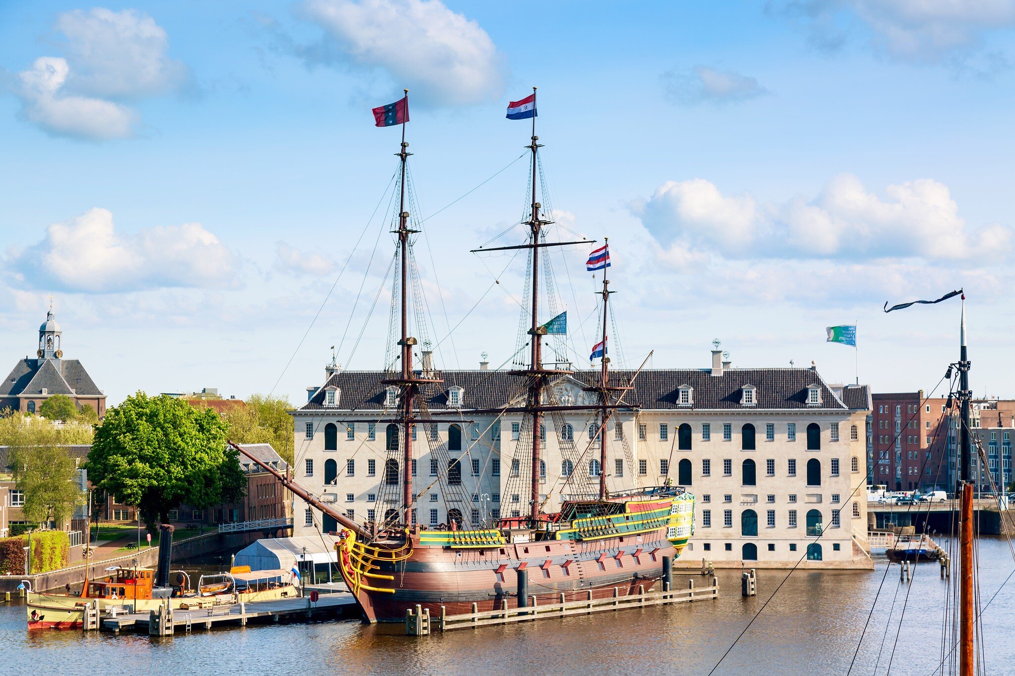 View of the National Maritime Museum in Amsterdam, with an old replica sailing ship in the foreground.