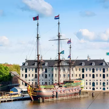 View of the National Maritime Museum in Amsterdam, with an old replica sailing ship in the foreground.