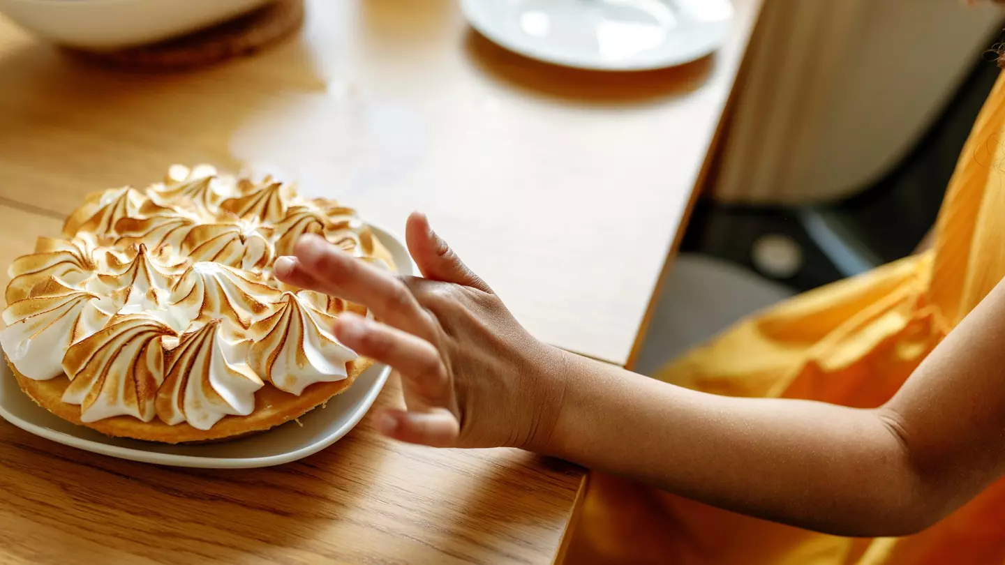 Hand of young girl about to touch a meringue pie
