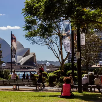 Tourist enjoying the view of Sydney Opera house from a shady spot at First Fleet Park in Circular Quay. Sydney, Australia.