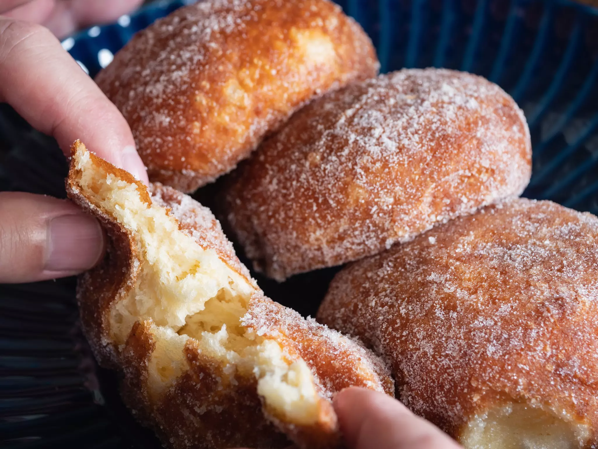 Sugar-coated donuts being torn open to reveal their fluffy interior