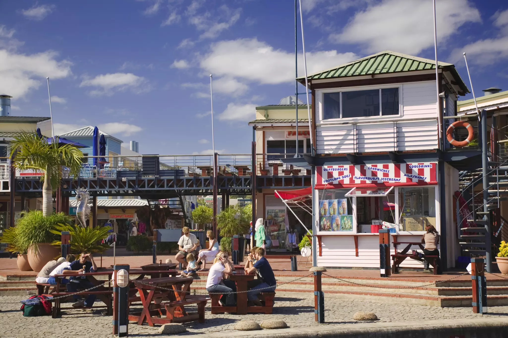 People socializing and eating at picnic tables on a pier