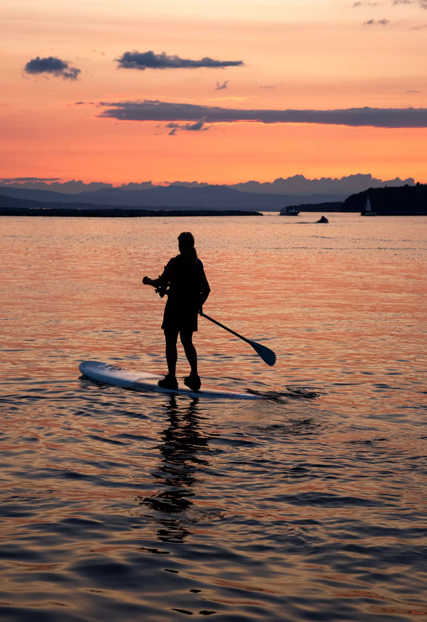 Woman practicing Paddle Board at sunset on lake Champlain, Vermont,