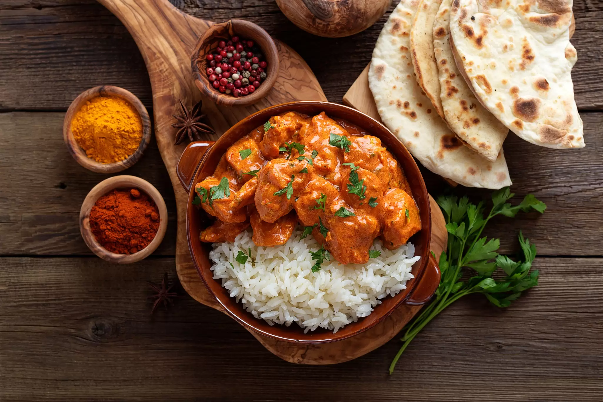 Chicken tikka masala in a clay plate with rice and naan bread. nelea33/Shutterstock
