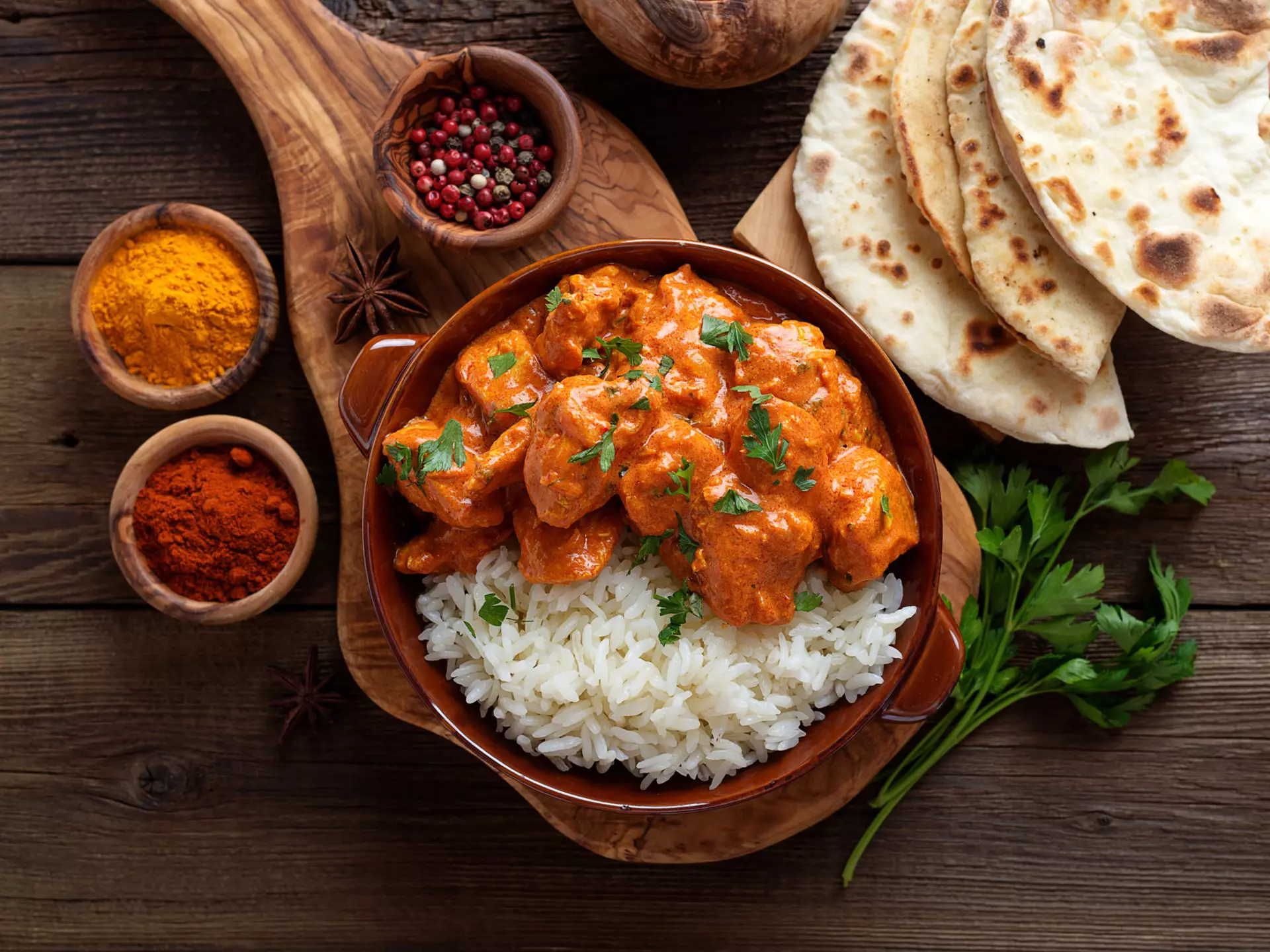 Chicken tikka masala in a clay plate with rice and naan bread. nelea33/Shutterstock
