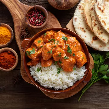 Chicken tikka masala in a clay plate with rice and naan bread. nelea33/Shutterstock