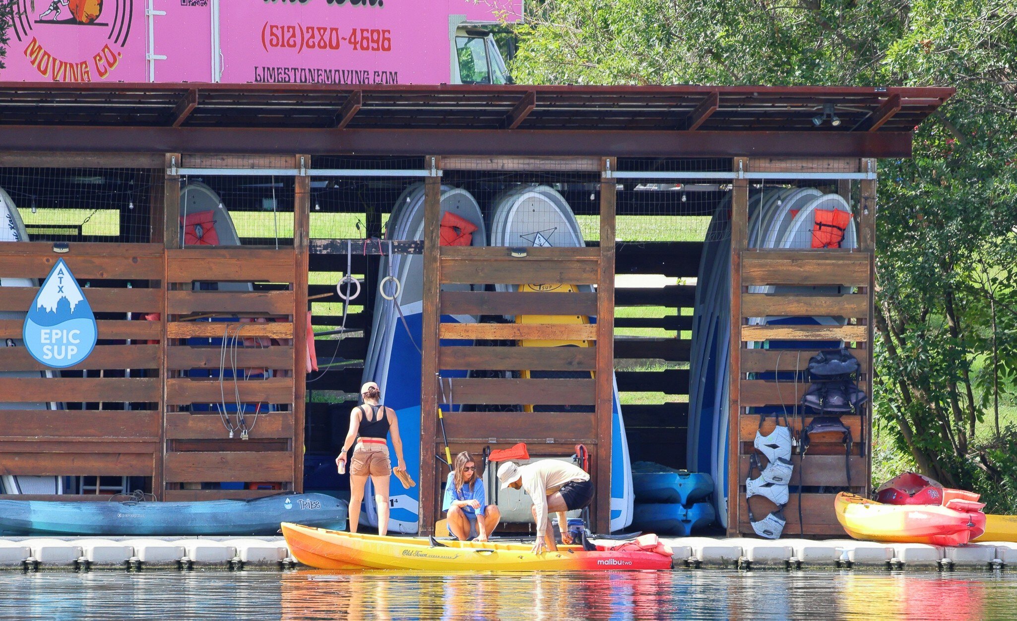 People stand on stand-up kayak boards on a lake in Austin