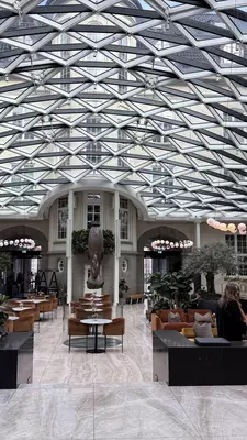 Wide shot of a hotel lobby with modern glass-and-steel ceiling.