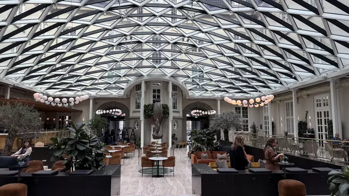 Wide shot of a hotel lobby with modern glass-and-steel ceiling.