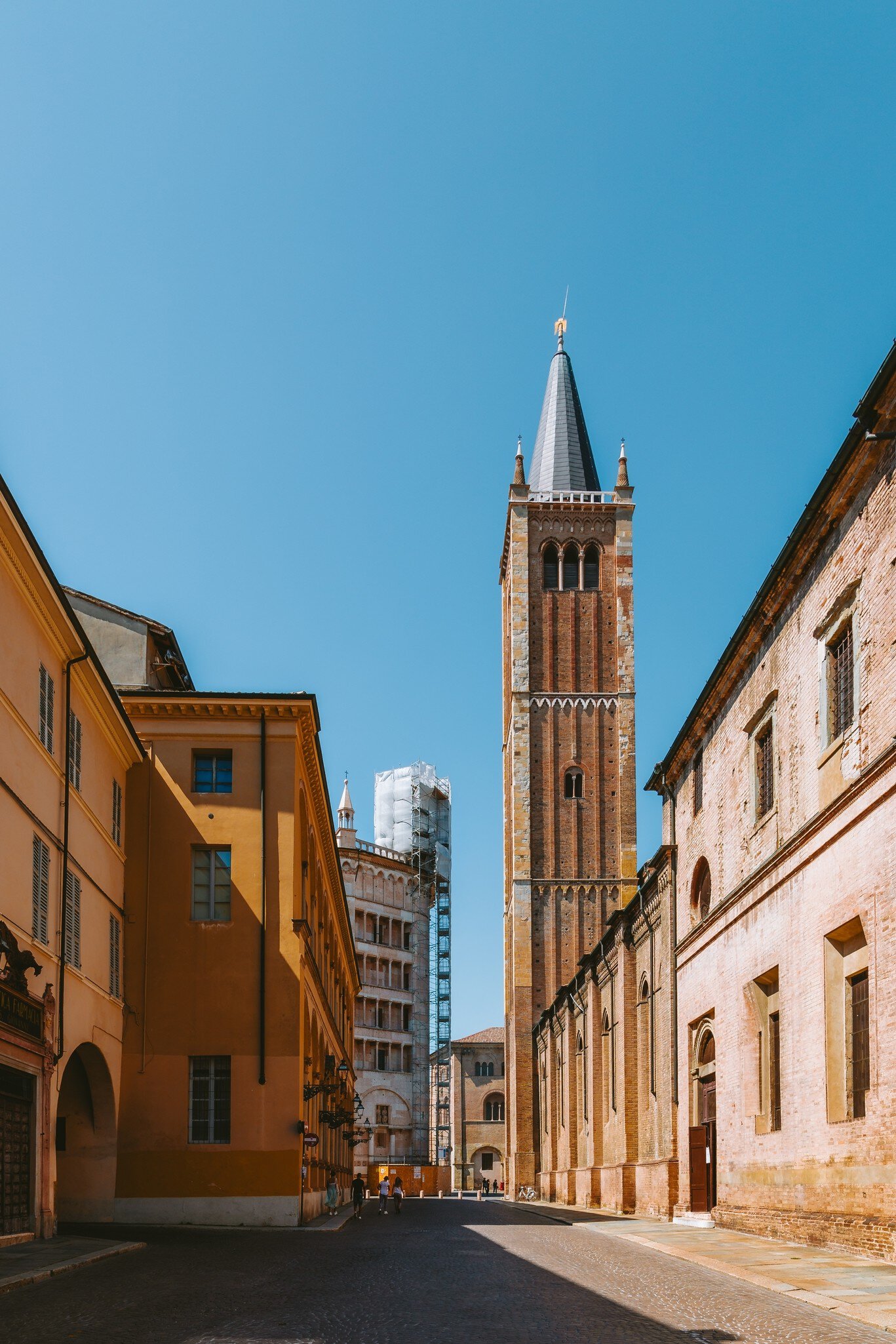 Parma's Cathedral bell tower dominates the skyline, bathed in warm sunlight on an Italian summer day, showcasing the city's rich architecture.