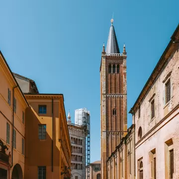 Parma's Cathedral bell tower dominates the skyline, bathed in warm sunlight on an Italian summer day, showcasing the city's rich architecture.