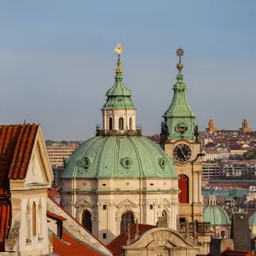 A view of the dome and bell tower of St.Nicholas Church and rooftops of Nerudova street. Prague, Czech Republic.