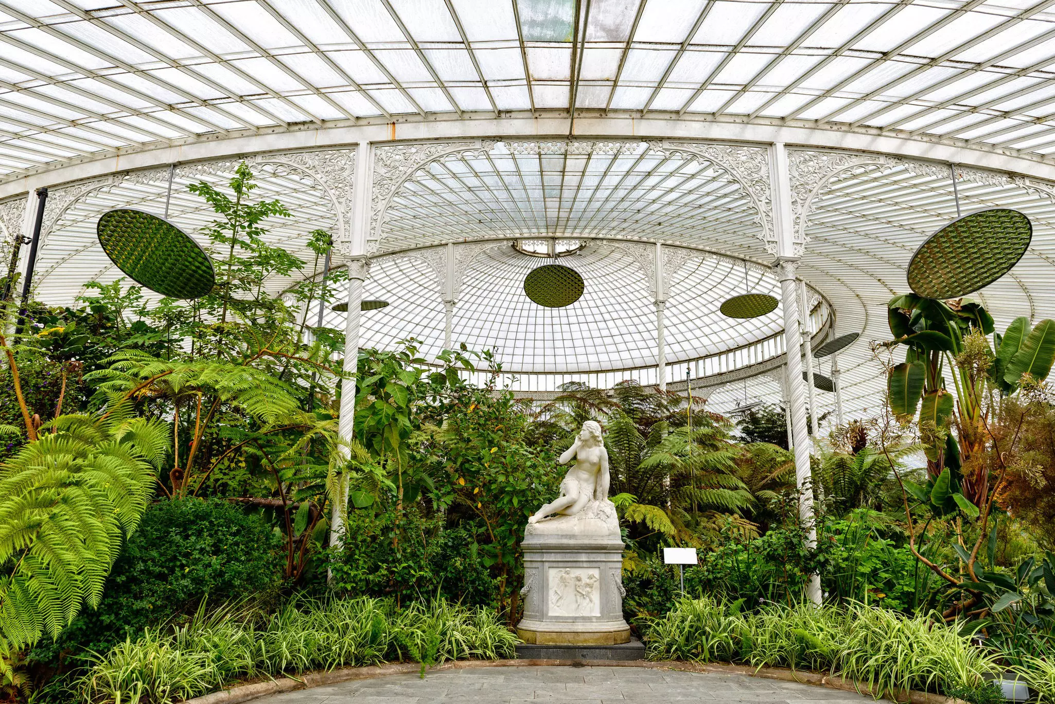 A statue and tropical plants inside the Kibble Palace glasshouse at the Botanic Gardens in Glasgow, Scotland.
