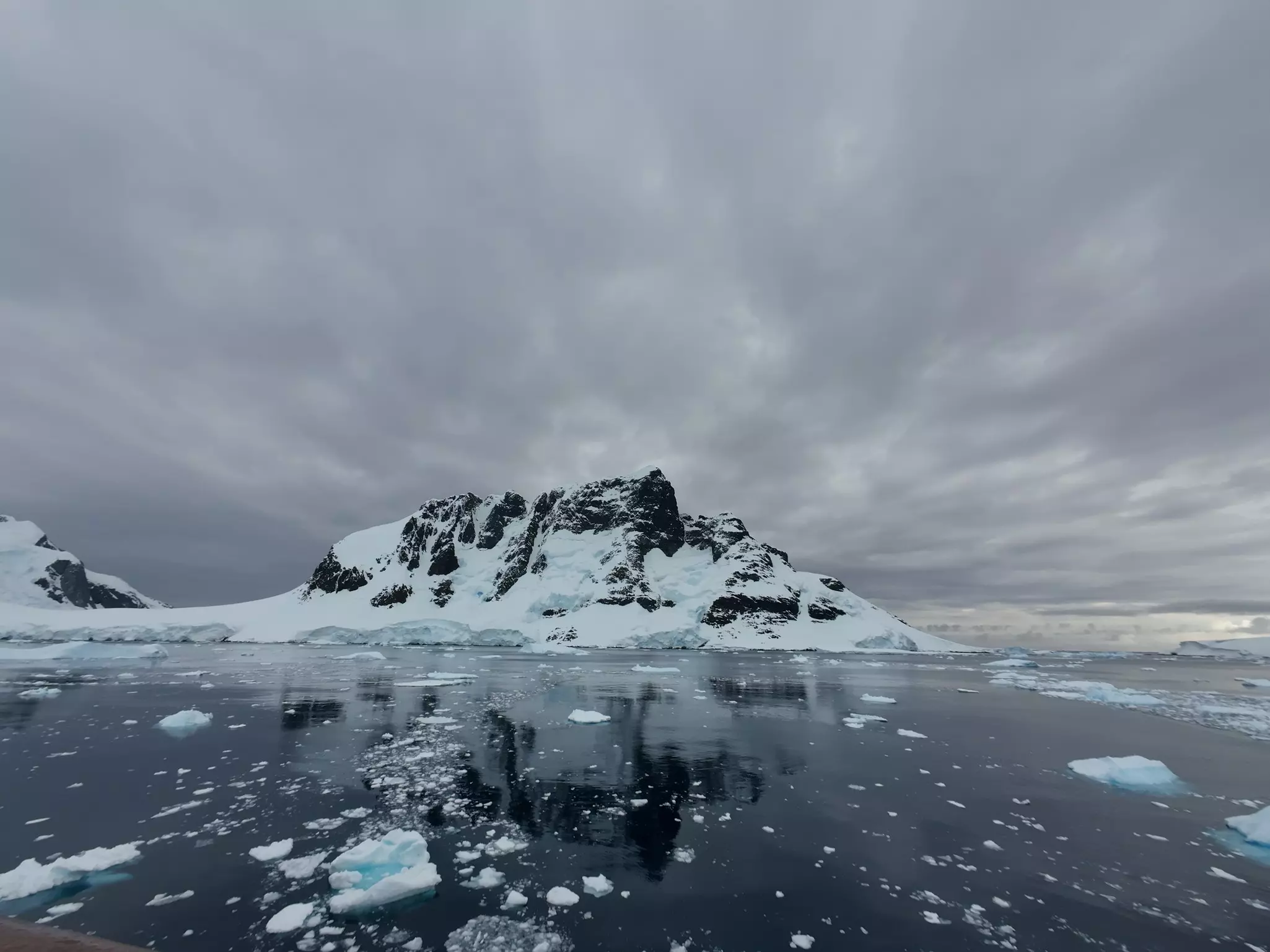 Snow-covered mountains and water on an overcast day in Lemaire Channel, Antarctica