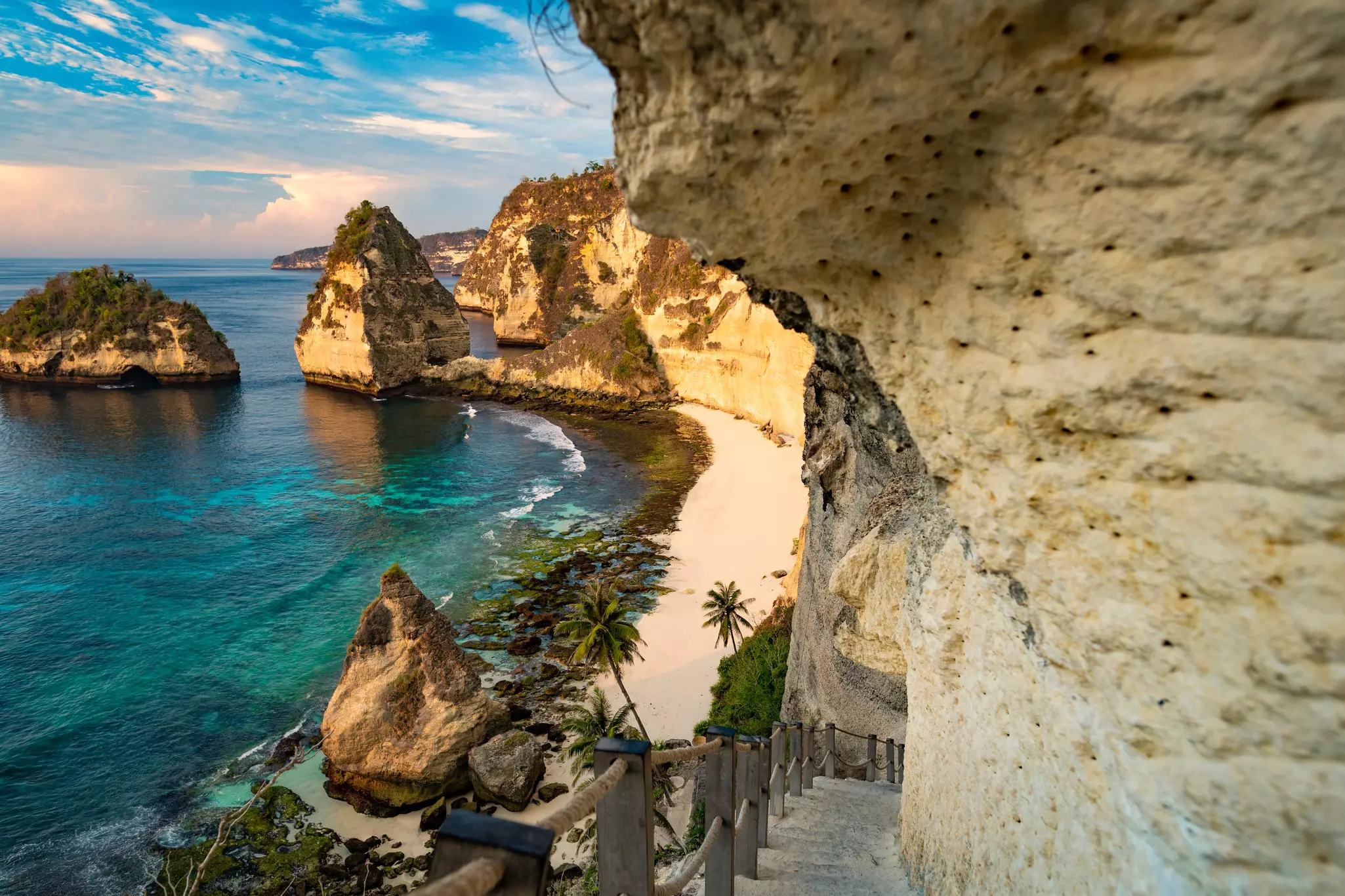 A small sandy beach in the shadow of a huge cliff in Bali.
