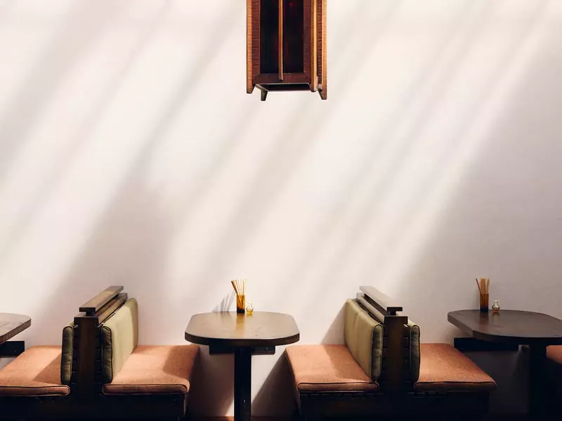 Simple, cushioned booths with dark wood oval tables at a restaurant