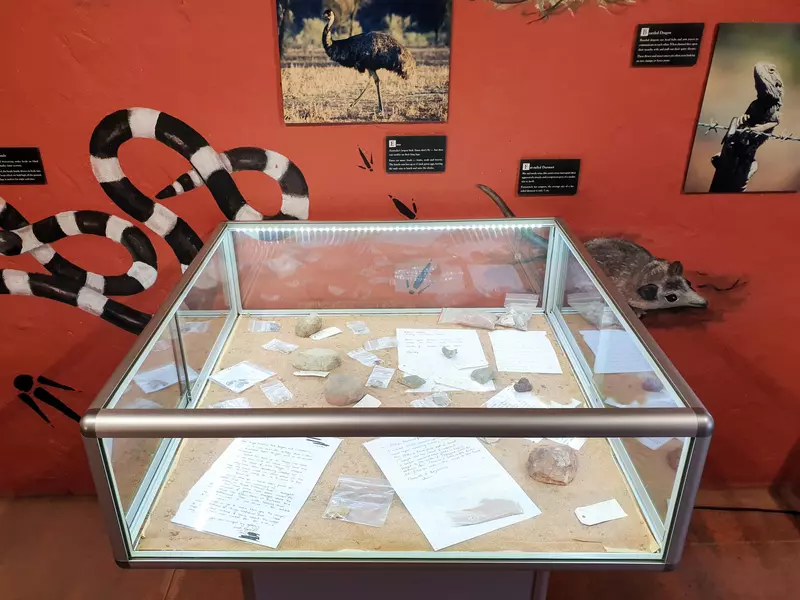 A glass case filled with rocks, hand written letters and various tags