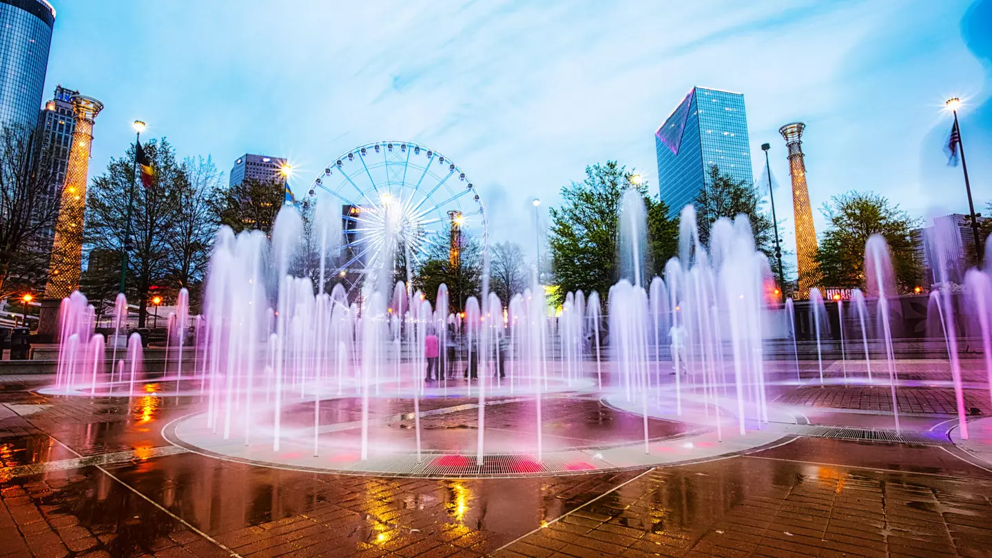 The colorfully lit fountain at Centennial Olympic Park with a Ferris wheel in the background