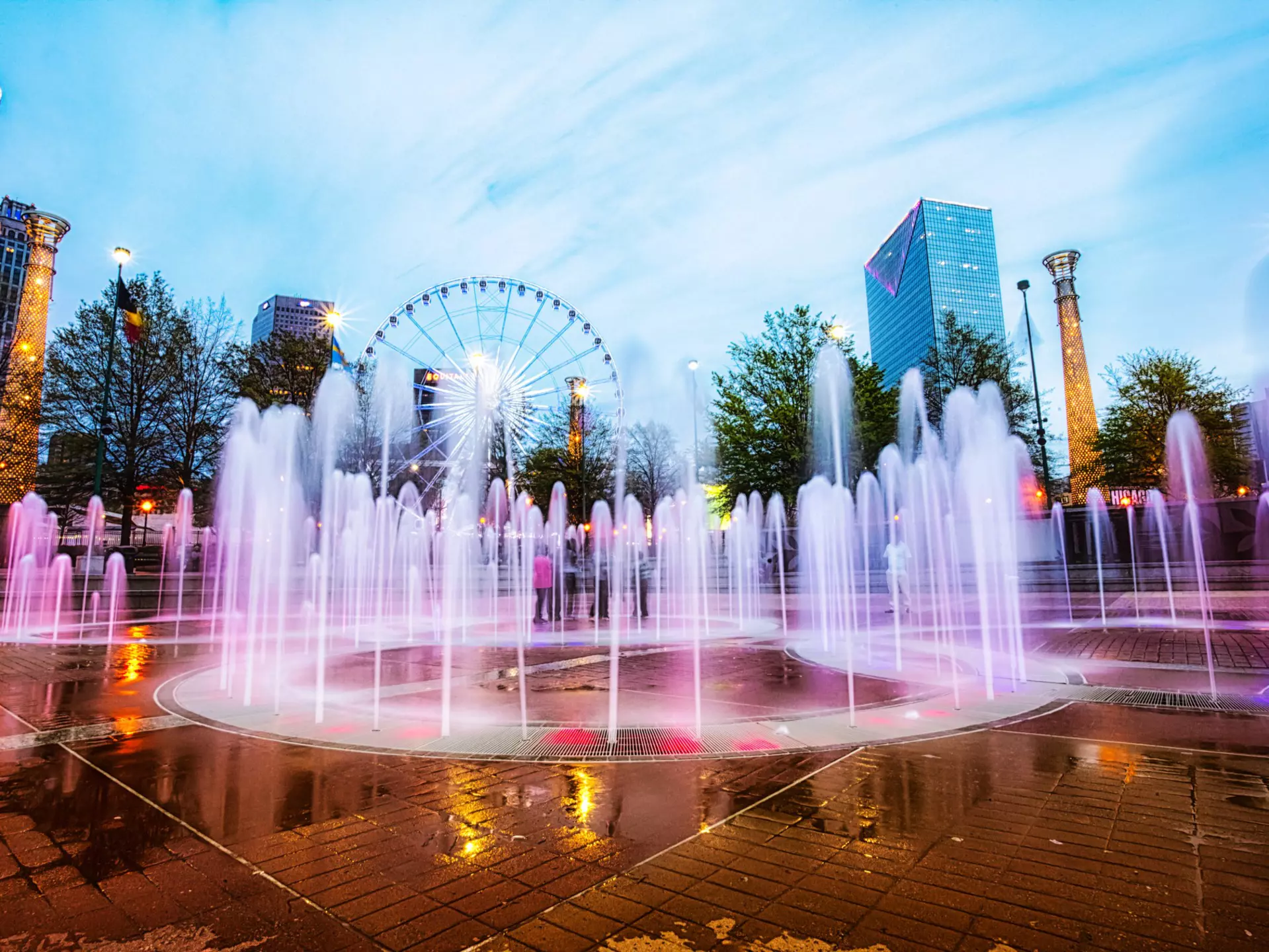 The colorfully lit fountain at Centennial Olympic Park with a Ferris wheel in the background