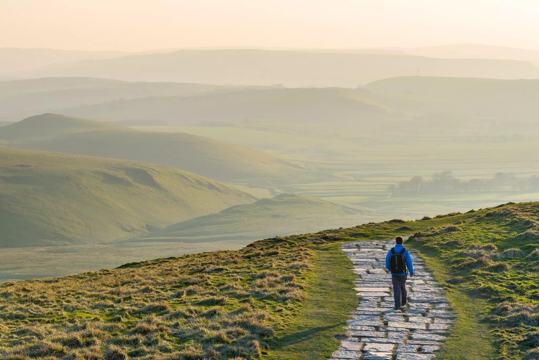 A hiker on the stone path at Mam Tor in Peak District National Park, England