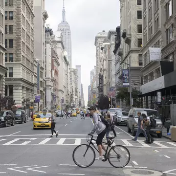 Pedestrians, cabs and cyclists at the intersection of Fifth Ave and 18th St in NYC.