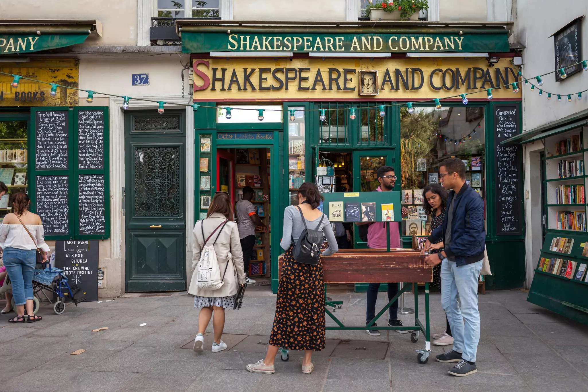 People looking in a bin of books set up outside of the Shakespeare & Company bookstore in Paris.