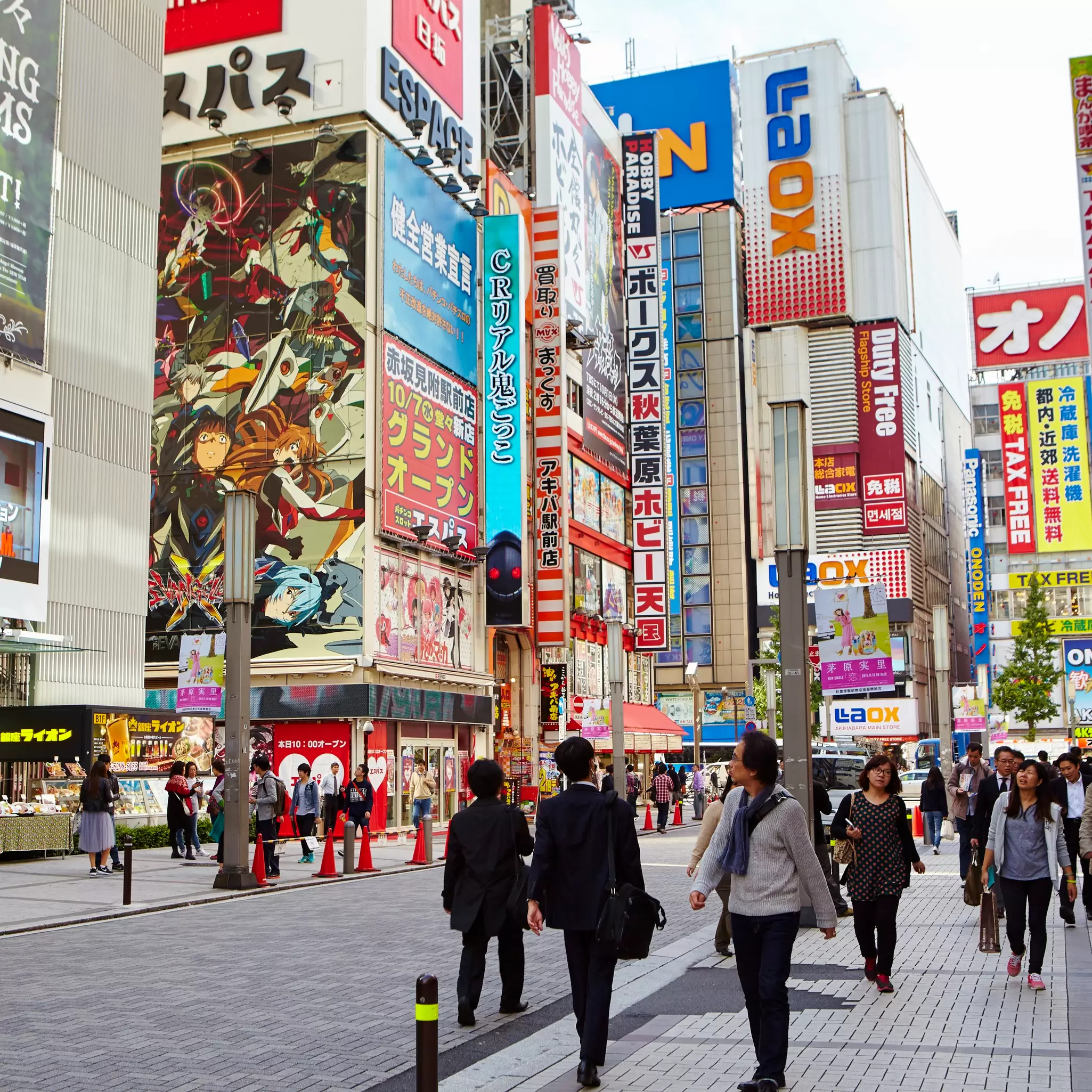 People walking on an Akihabara street near a building with manga imagery on one wall