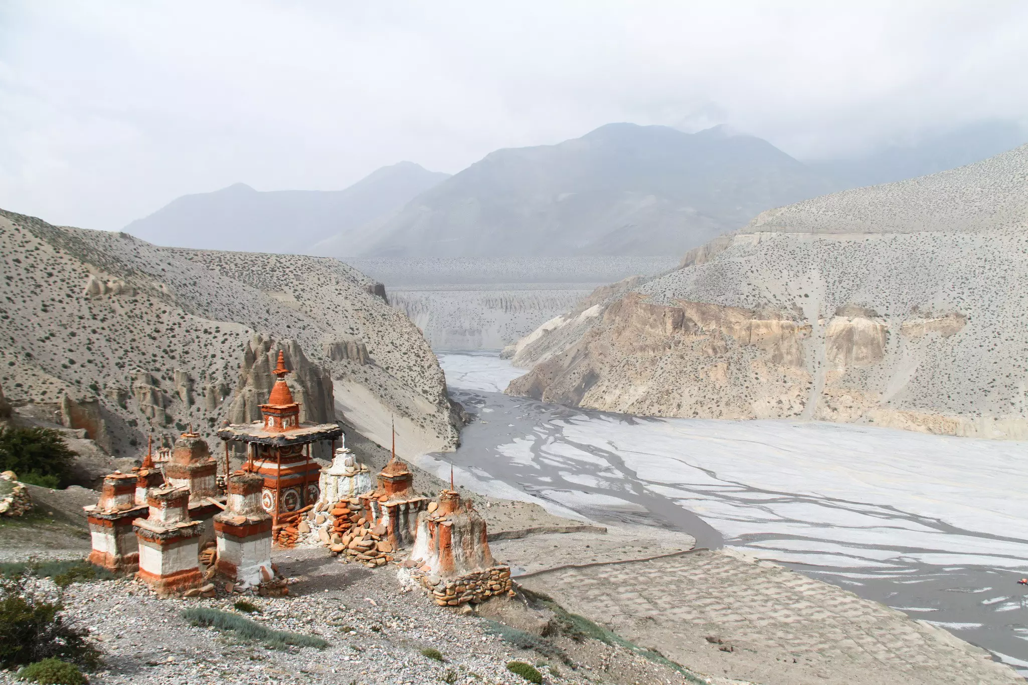Buddhist stupas on a hill at the top of a river valley.