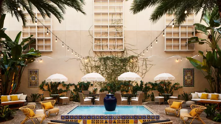 The pretty courtyard at Pasadena Hotel & Pool with soft lights hanging above umbrella-topped seating areas